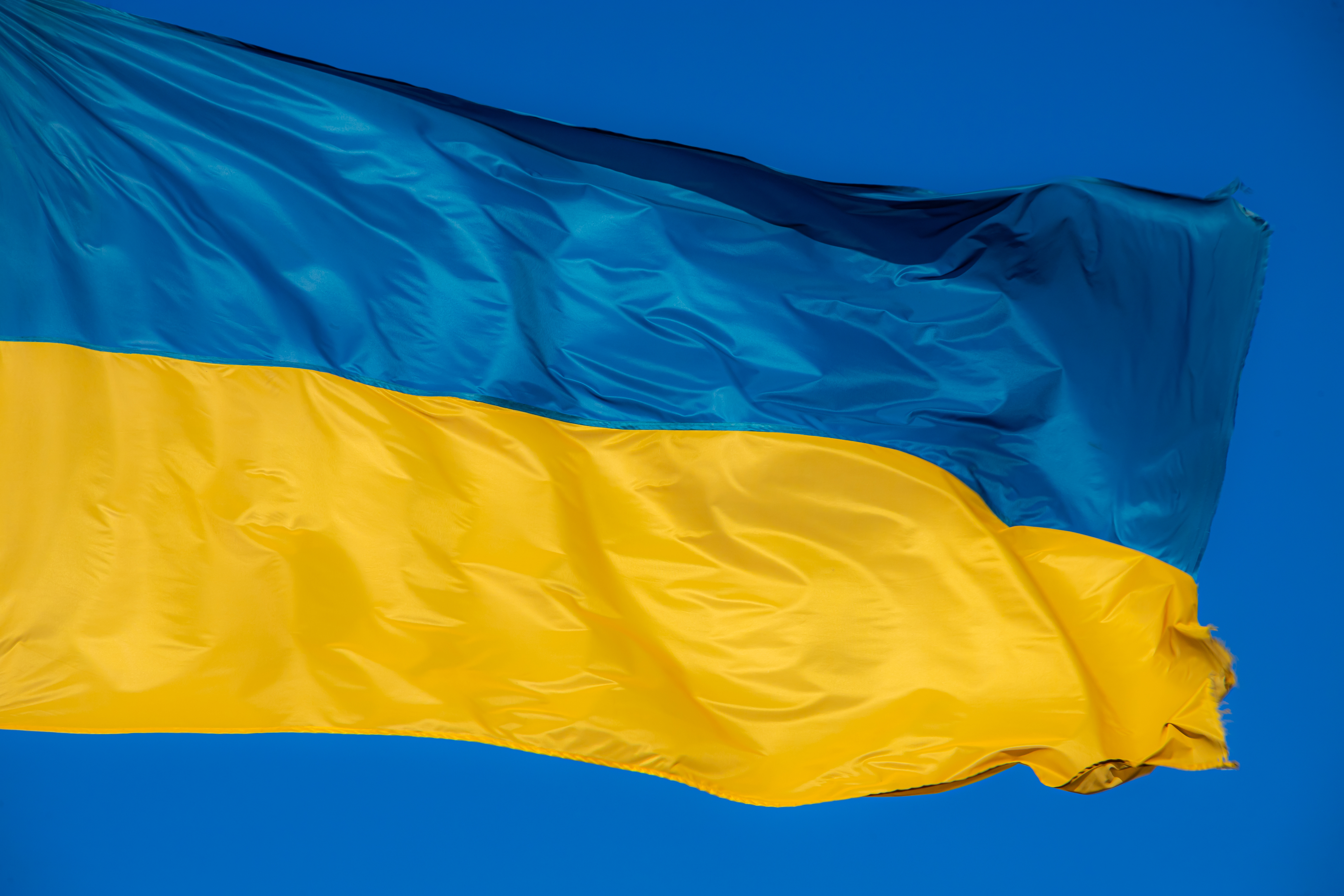 Eine ukrainische Flagge wehr im Wind vor einem blauen Himmel