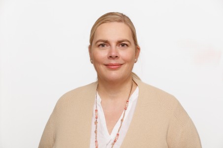  Portrait von Stefanie Arens. Sie trägt eine beige Jacke und lächelt.