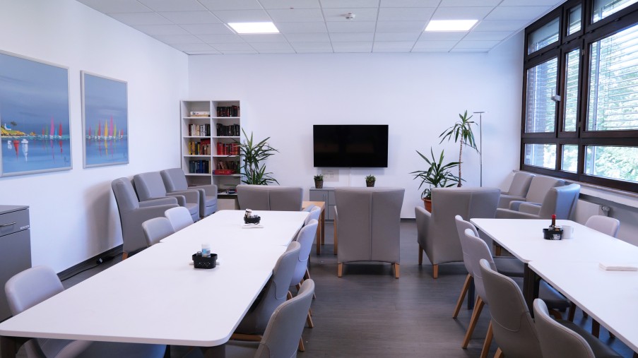 Ein Raum mit Tischen einer Sofaecke, Fernseher und Bücherregal