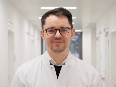 Portrait von Dr. Mayer. Er trägt einen weißen Kittel und lächelt.