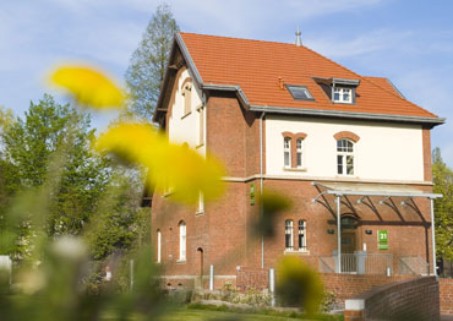 Ein Bild von Haus 21, einem roten Backsteinhaus, vor blauem Himmel