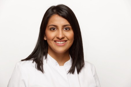 Porträt von Irini Chaliani. Sie trägt einen weißen Kittel und lächelt in die Kamera.