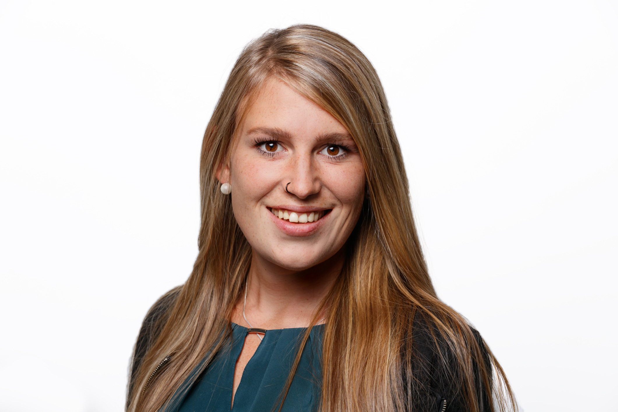 Ein Portrait einer Frau mit langen dunkelblonden Haaren und einer blauen Bluse