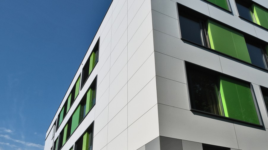 Seitliche Ansicht von einem weißen Gebäude mit grünen Akzenten