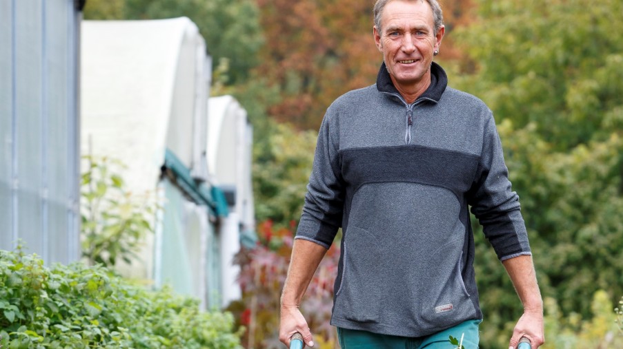 eine Mann mit einer Schubkarre mit Gartenabfällen