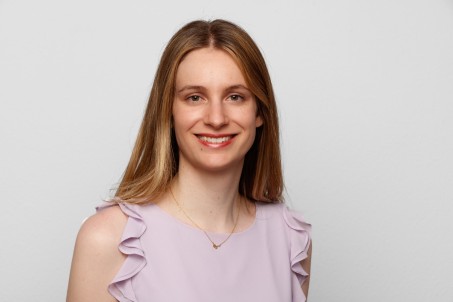 Porträt von Frau Brouzou in lilafarbener Bluse vor weißem Hintergrund