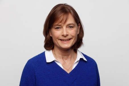 Frau mit schulterlangen Haaren und einem blauen Pullover lächelt