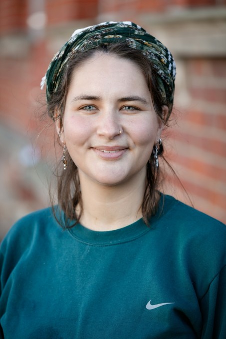 Portrait von Frau Mansfeld-Shiah vor einer Backsteinwand, sie schaut in die Kamera und lächelt 