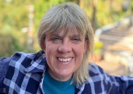 Eine Frau mit schulterlangen blonden Haaren und einem blaukariertem Hemd