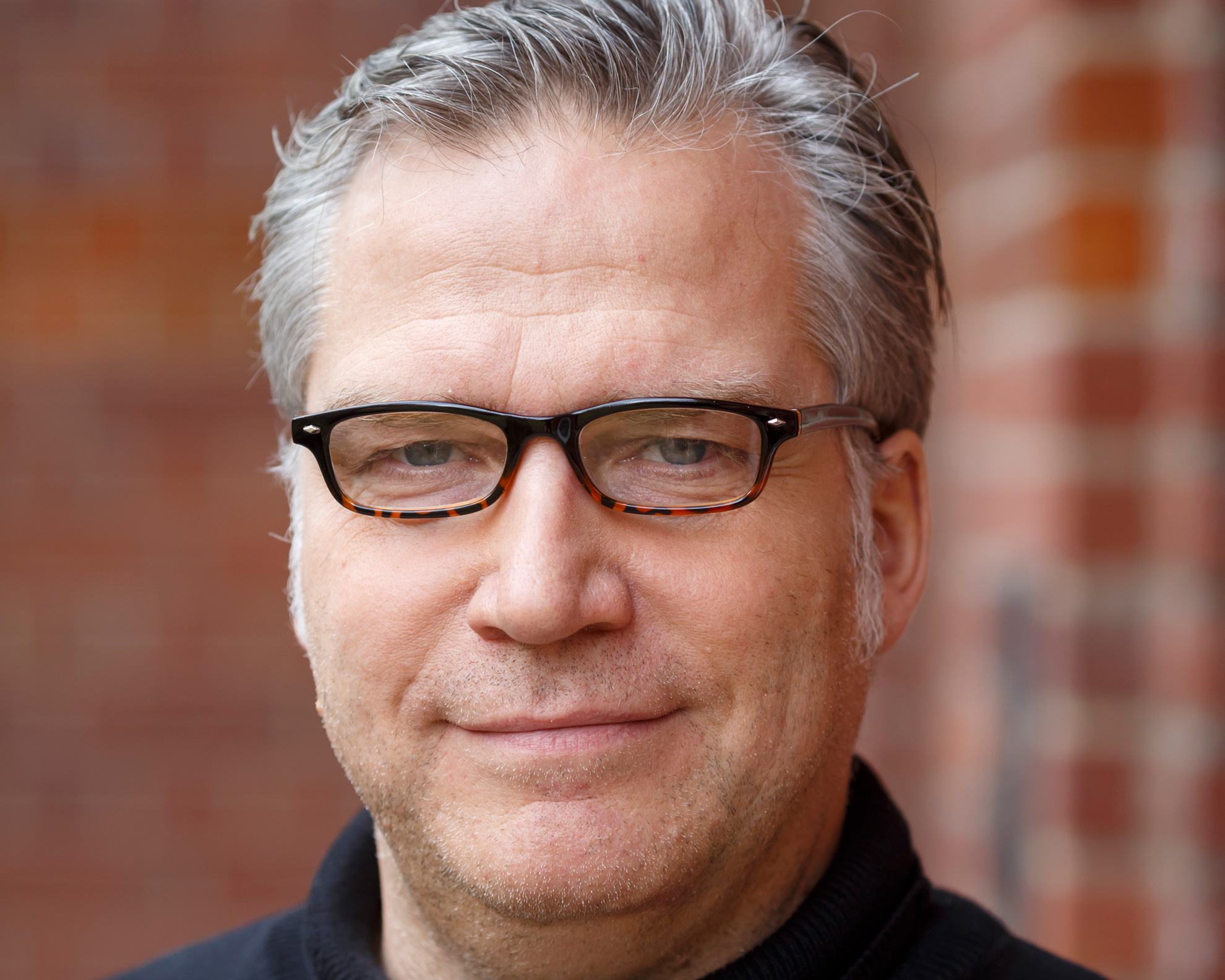 Ein Mann mit Brille und grauen Haaren