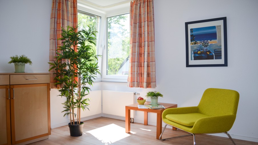 Zimmer mit Sessel, Pflanze und Sideboard