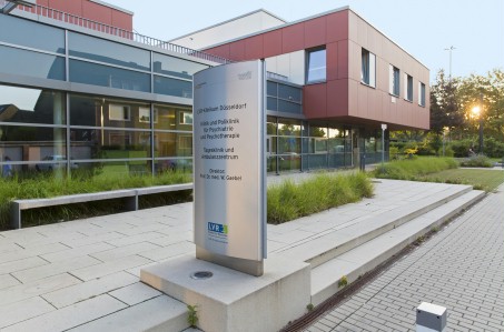 Foto des Eingangsbereiches des TAZ-Gebäudes. Sonne geht hinter Bäumen unter.