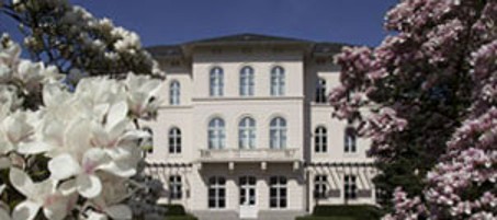 Eine Person steht am Tresen der Notaufnahme und liest eine versichertenkarte ein. Hinter dem Tresen steht eine weitere Person, die die Anmeldung in Empfang nimmt